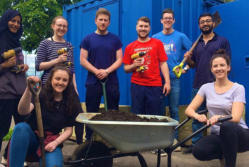 corporate volunteering group pose for photo during session helping community garden