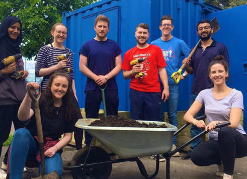 corporate volunteering group pose for photo during session helping community garden