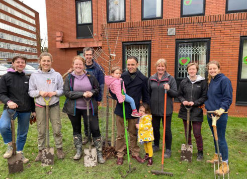 group posing for camera as part of tree planting session at Manchester GP surgery